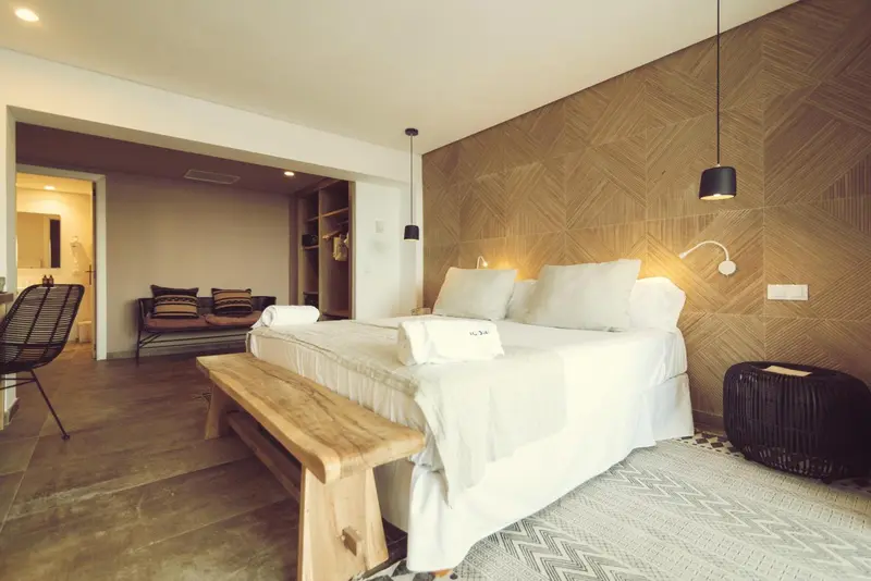 Une chambre lumineuse avec un grand lit et un espace salon.