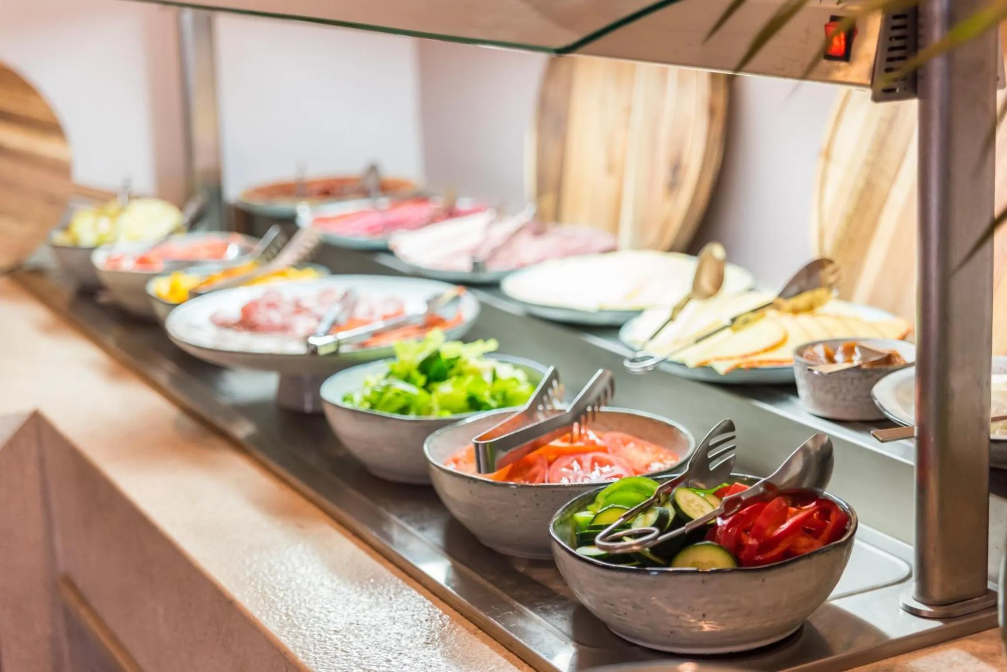 Présentation de salades, charcuteries et fromages sur un buffet.