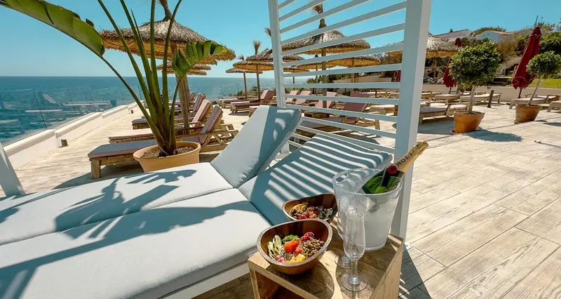 Transats et table basse avec boissons et fruits sur une terrasse ensoleillée.