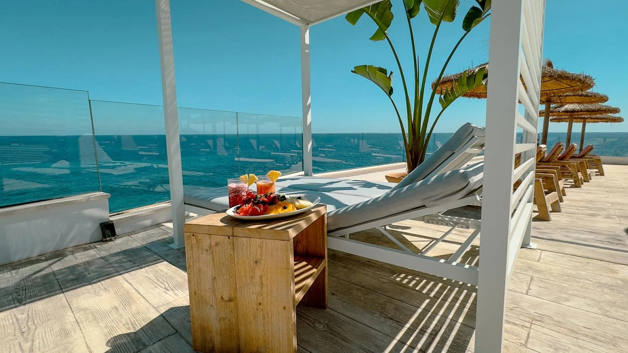 Terrasse avec transats, table basse et vue sur la mer.