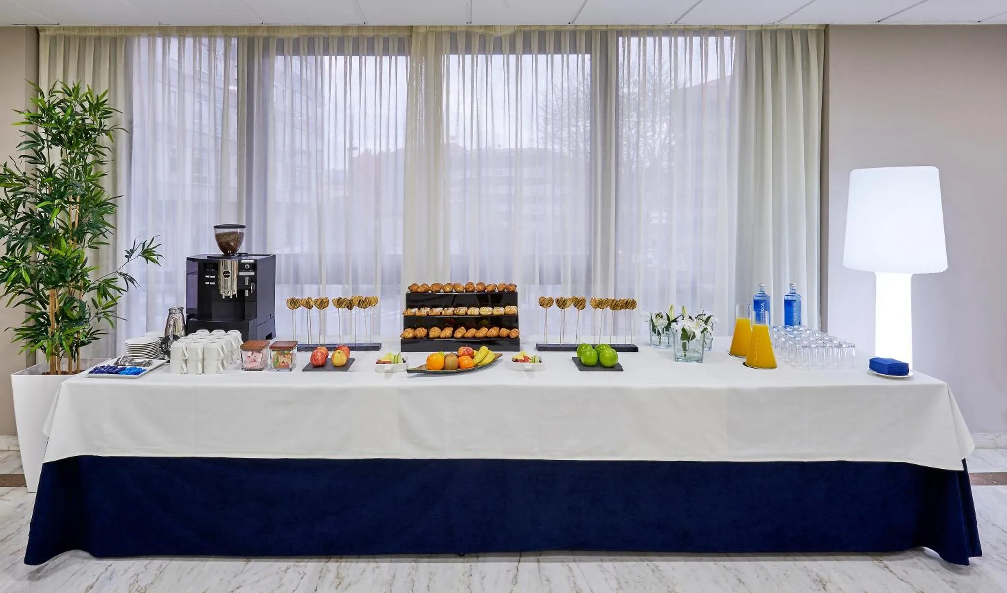 Une table recouverte d'une nappe blanche présente une sélection de boissons et de pâtisseries.