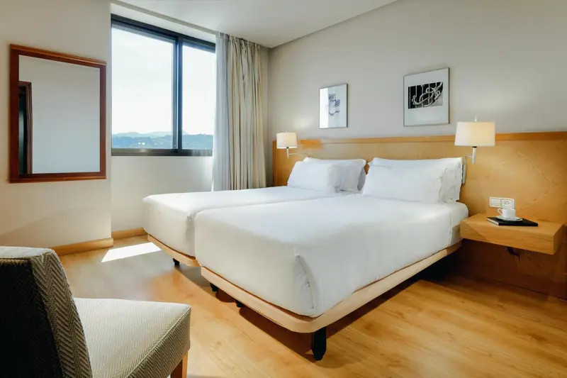 Une chambre lumineuse avec deux lits simples et un grand miroir.