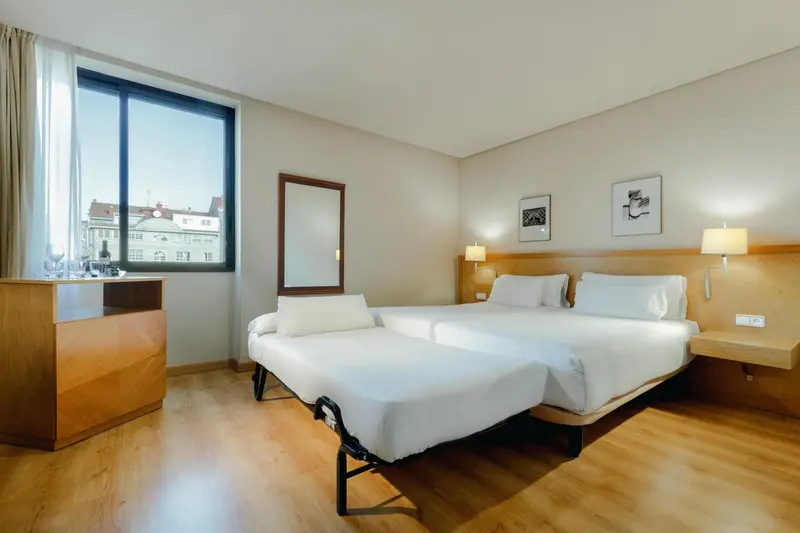 Une chambre lumineuse avec deux lits simples et une commode en bois.
