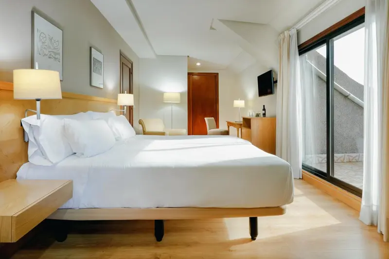 Une chambre lumineuse avec un grand lit et un accès à une terrasse.