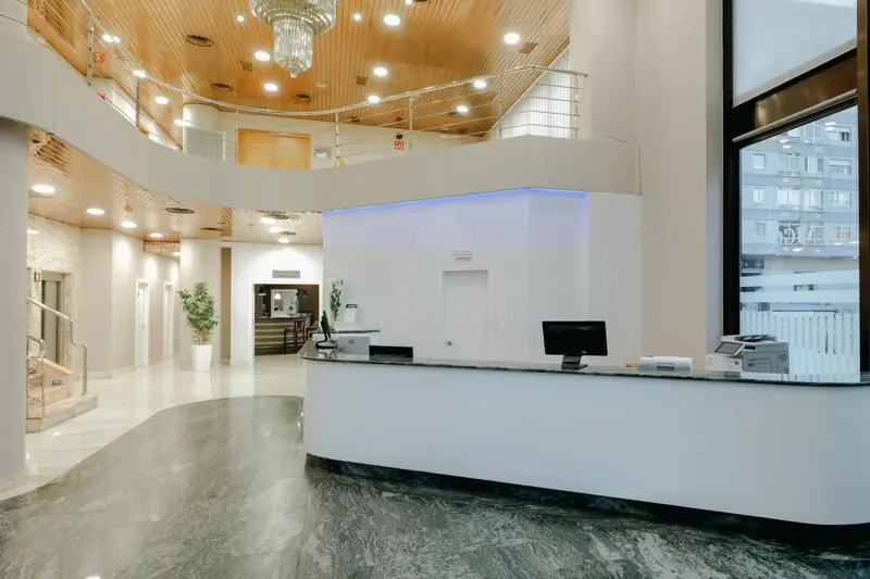 Hall d'accueil lumineux avec comptoir d'enregistrement et éclairage décoratif.
