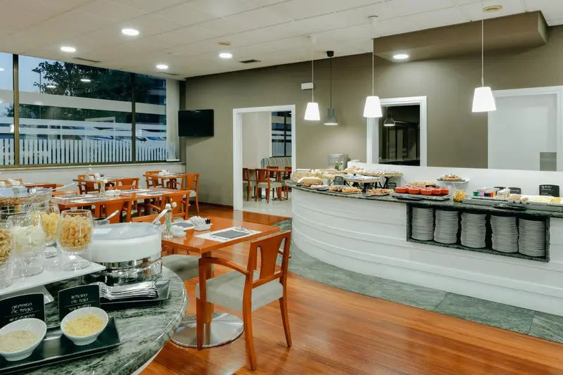 Une salle lumineuse avec un buffet de petit-déjeuner et des tables.