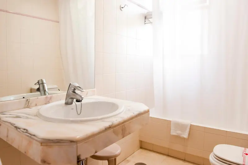 Lavabo sur un meuble en marbre dans une salle de bain claire.