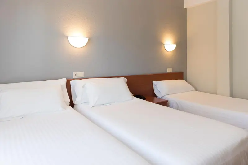 Deux lits simples avec oreillers blancs dans une chambre lumineuse.