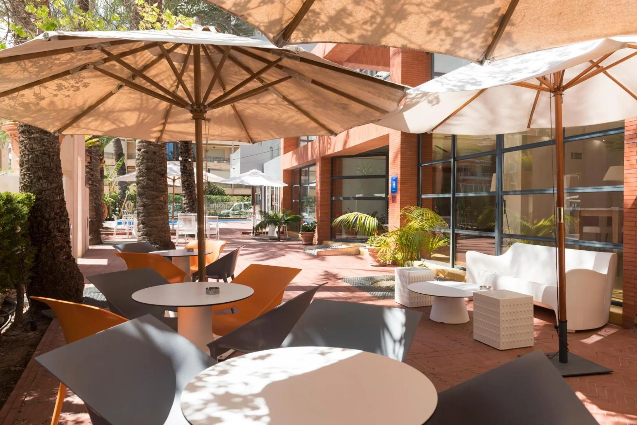 Terrasse ombragée avec mobilier de jardin et canapés blancs.