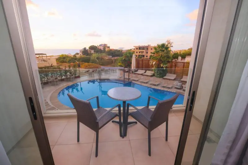 Terrasse avec mobilier de jardin donnant sur une piscine et la mer.