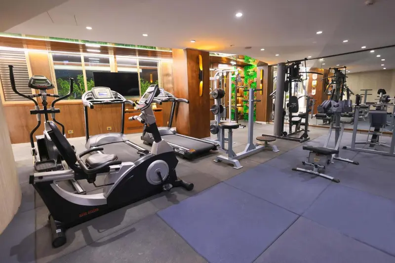 Une salle de sport lumineuse avec divers équipements de musculation et cardio.