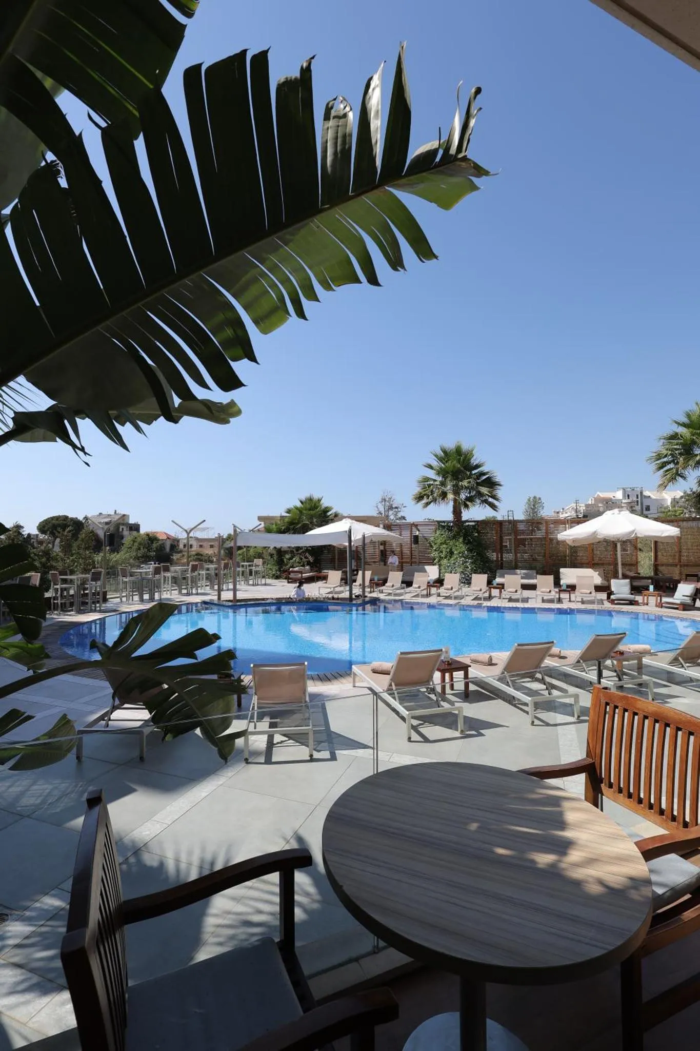 Une piscine bordée de transats et de parasols sous un ciel bleu.
