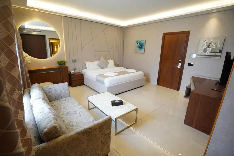 Chambre lumineuse avec un lit double, un canapé et un bureau.