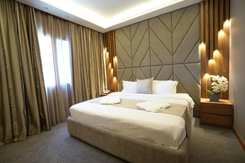 Une chambre lumineuse avec un grand lit et une décoration murale texturée.