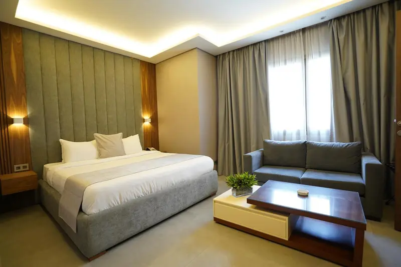 Une chambre lumineuse avec un grand lit et un coin salon.