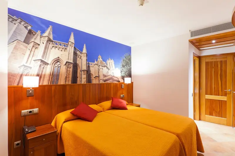 Chambre avec deux lits simples et un grand décor mural représentant une cathédrale.