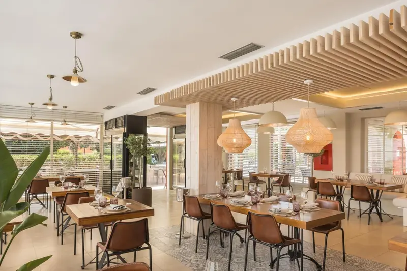 Une salle lumineuse avec des tables dressées pour un repas.