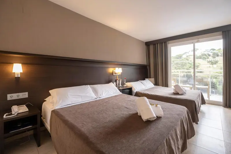 Une chambre lumineuse avec deux lits simples et une vue sur un paysage verdoyant.