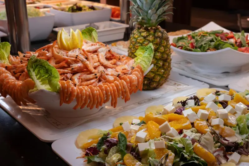 Présentation de salades et de fruits de mer frais sur un buffet.