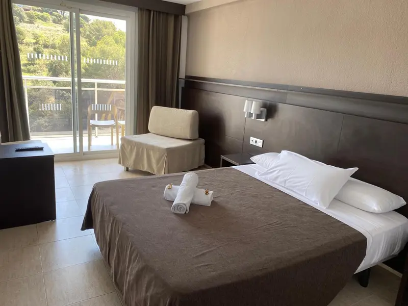 Une chambre avec un lit et un fauteuil face à une baie vitrée.