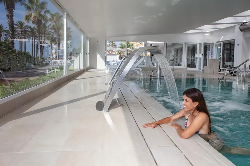 Une femme se détend dans une piscine intérieure avec un jet d'eau massant.