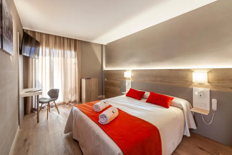 Une chambre lumineuse avec un grand lit et un bureau.