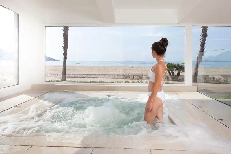 Une femme se détend dans un jacuzzi intérieur avec vue sur la plage.