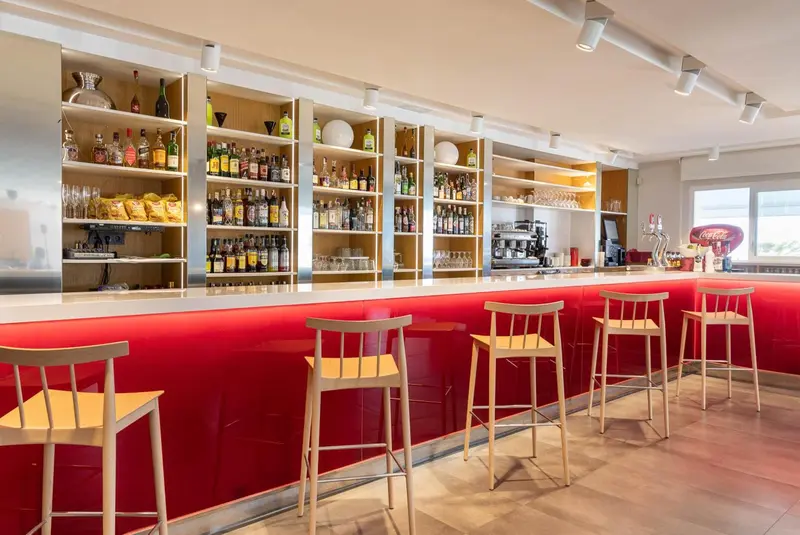 Un comptoir de bar moderne avec des bouteilles et des tabourets.