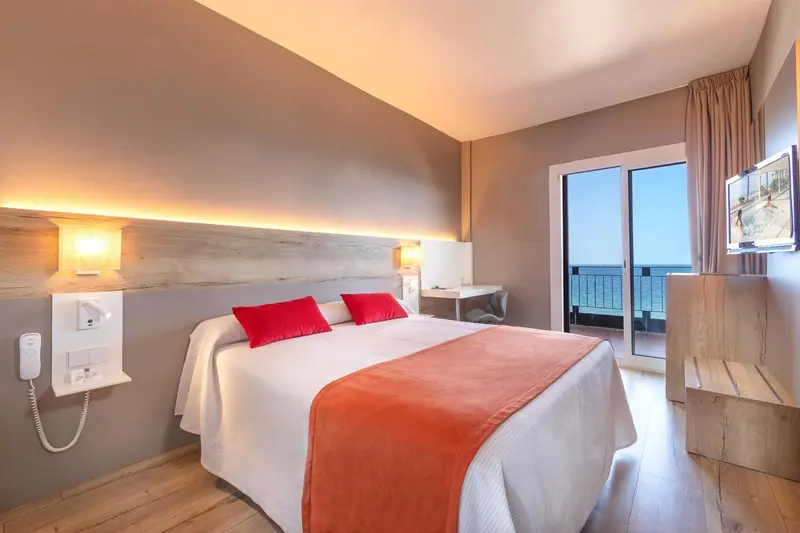 Chambre lumineuse avec un grand lit et une vue sur la mer.