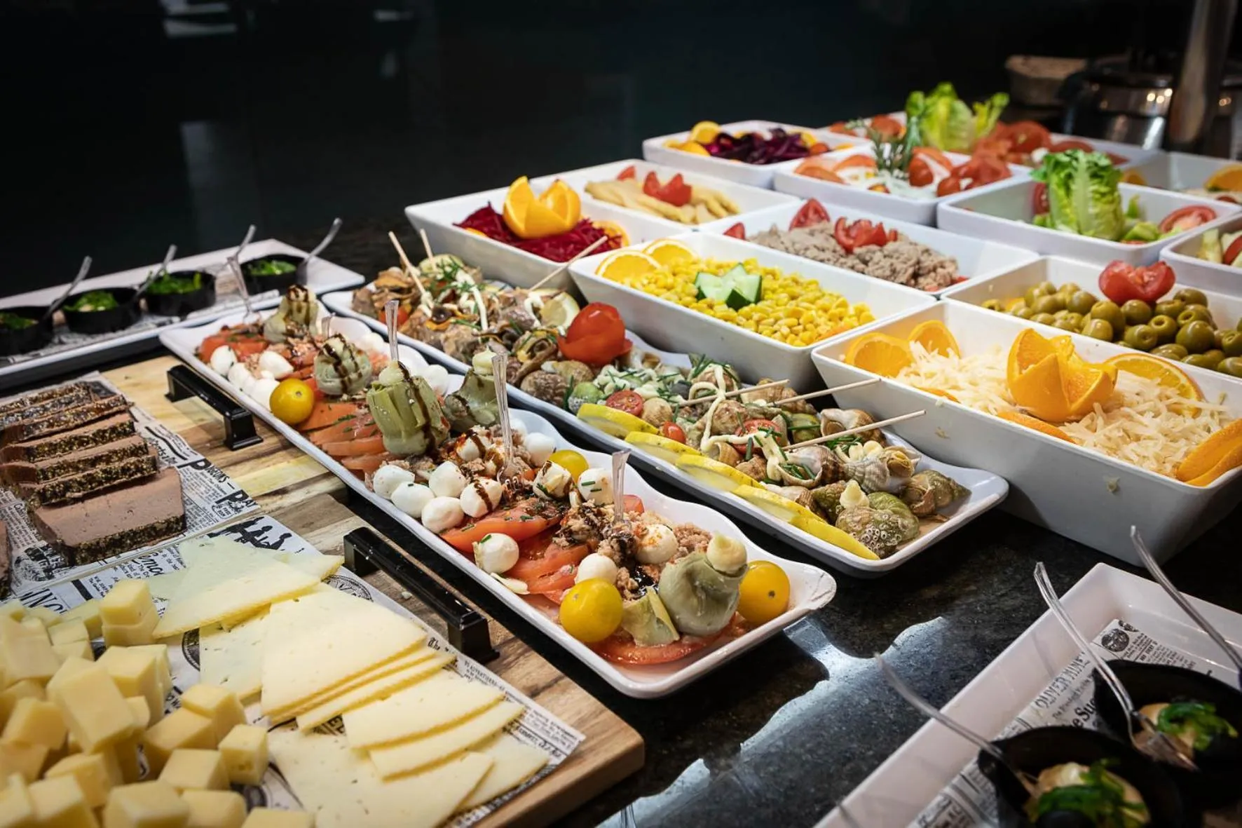 Un buffet propose une variété de salades, de charcuteries et de fromages.
