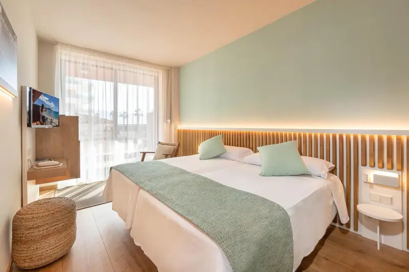 Une chambre lumineuse avec un grand lit et un fauteuil.