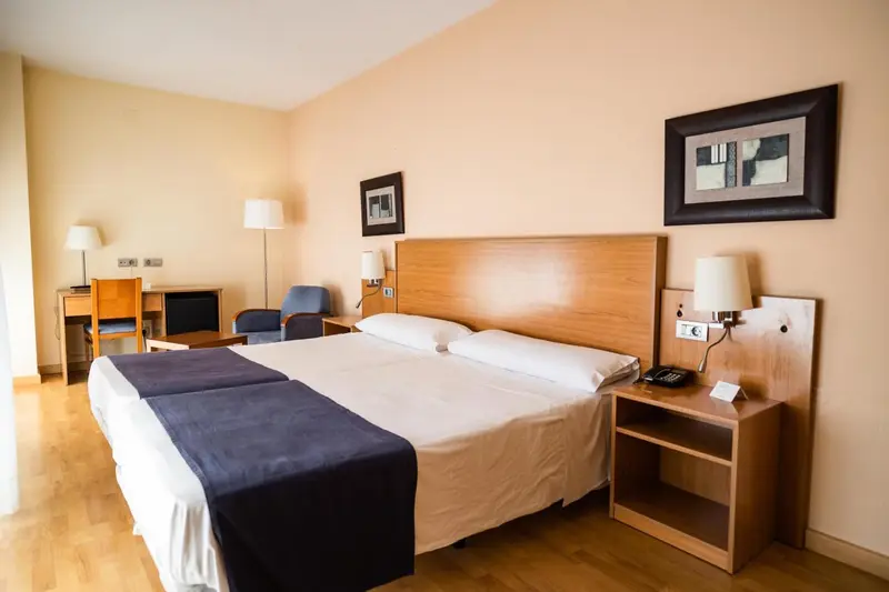 Une chambre d'hôtel lumineuse avec un grand lit et des tables de chevet.