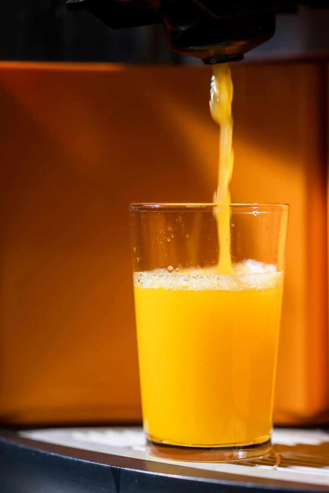 Un verre de jus d'orange est rempli par une machine distributrice.