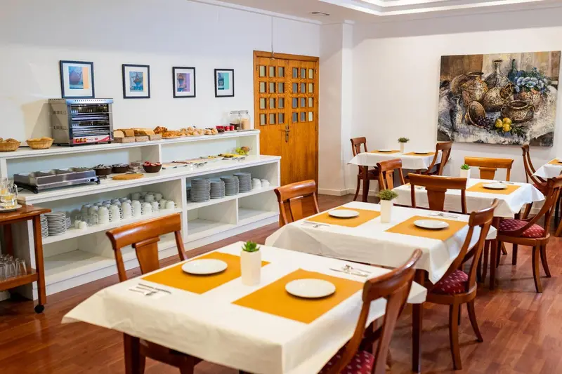 Une salle lumineuse avec des tables dressées pour le repas.