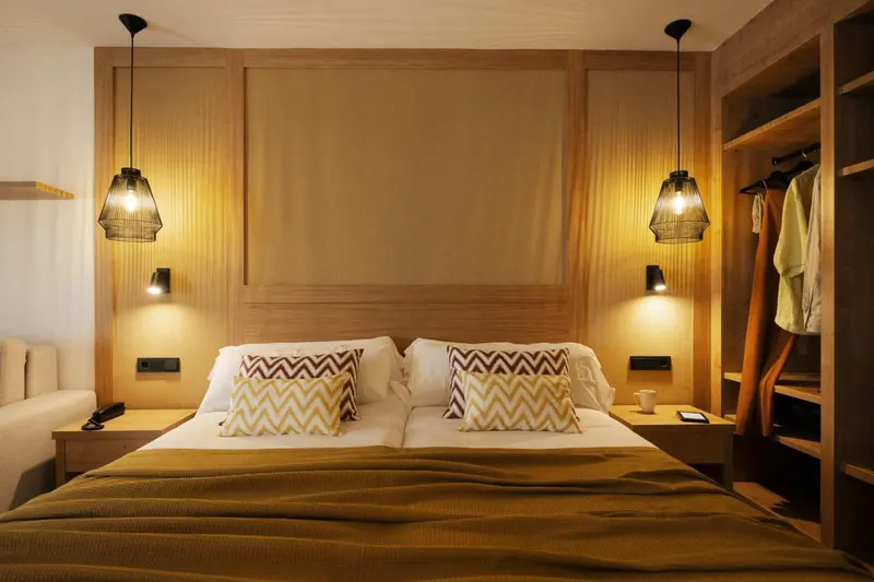 Une chambre avec un grand lit et des suspensions lumineuses.