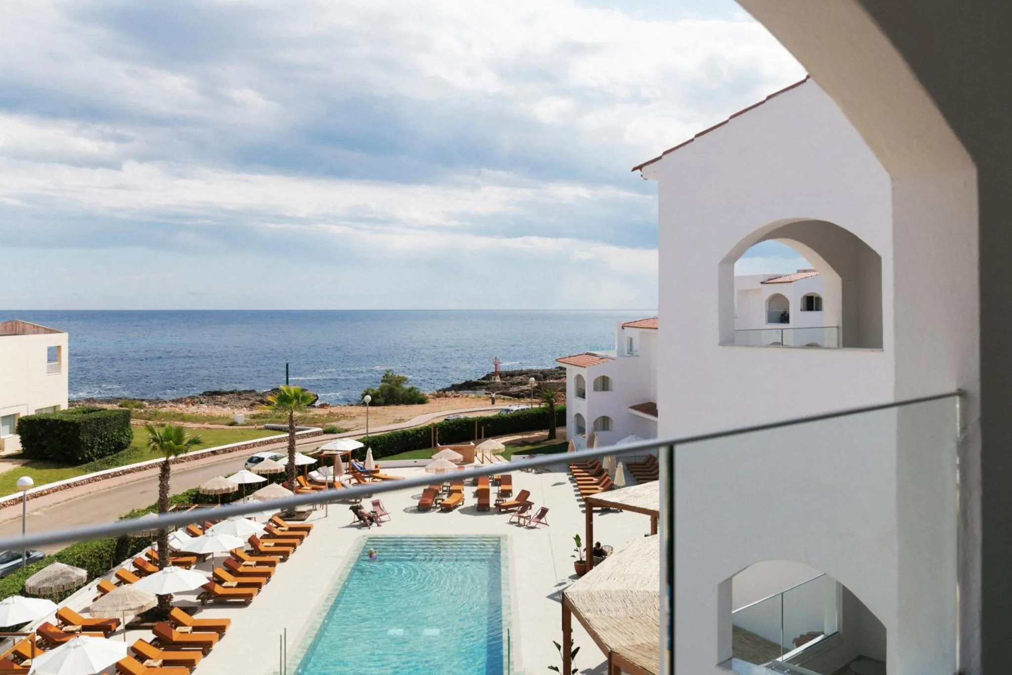 Vue sur la mer depuis un balcon avec piscine et transats.