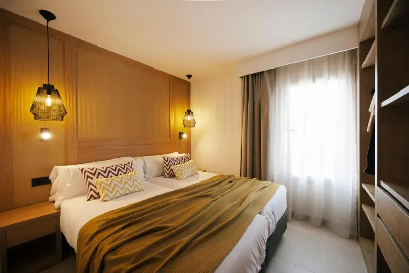 Une chambre lumineuse avec un grand lit recouvert d'une couverture jaune et de coussins décoratifs.