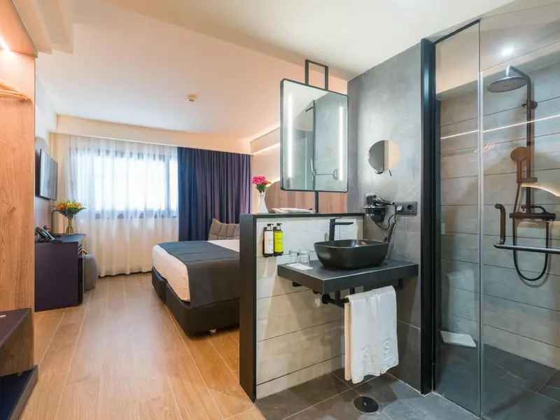 Une chambre lumineuse avec un lit et une salle de bain attenante.