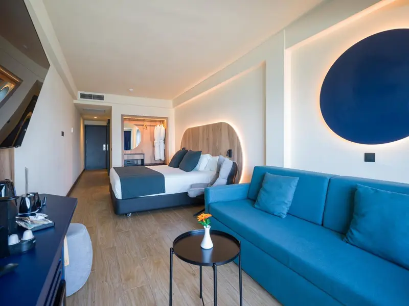 Une chambre lumineuse avec un canapé bleu et un grand lit.