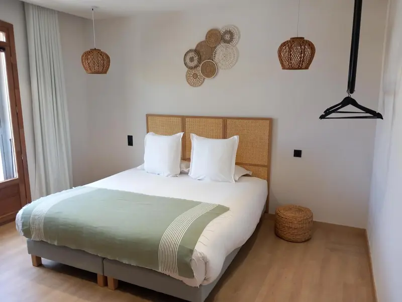 Une chambre lumineuse avec un grand lit recouvert d'une couette verte et de coussins blancs.