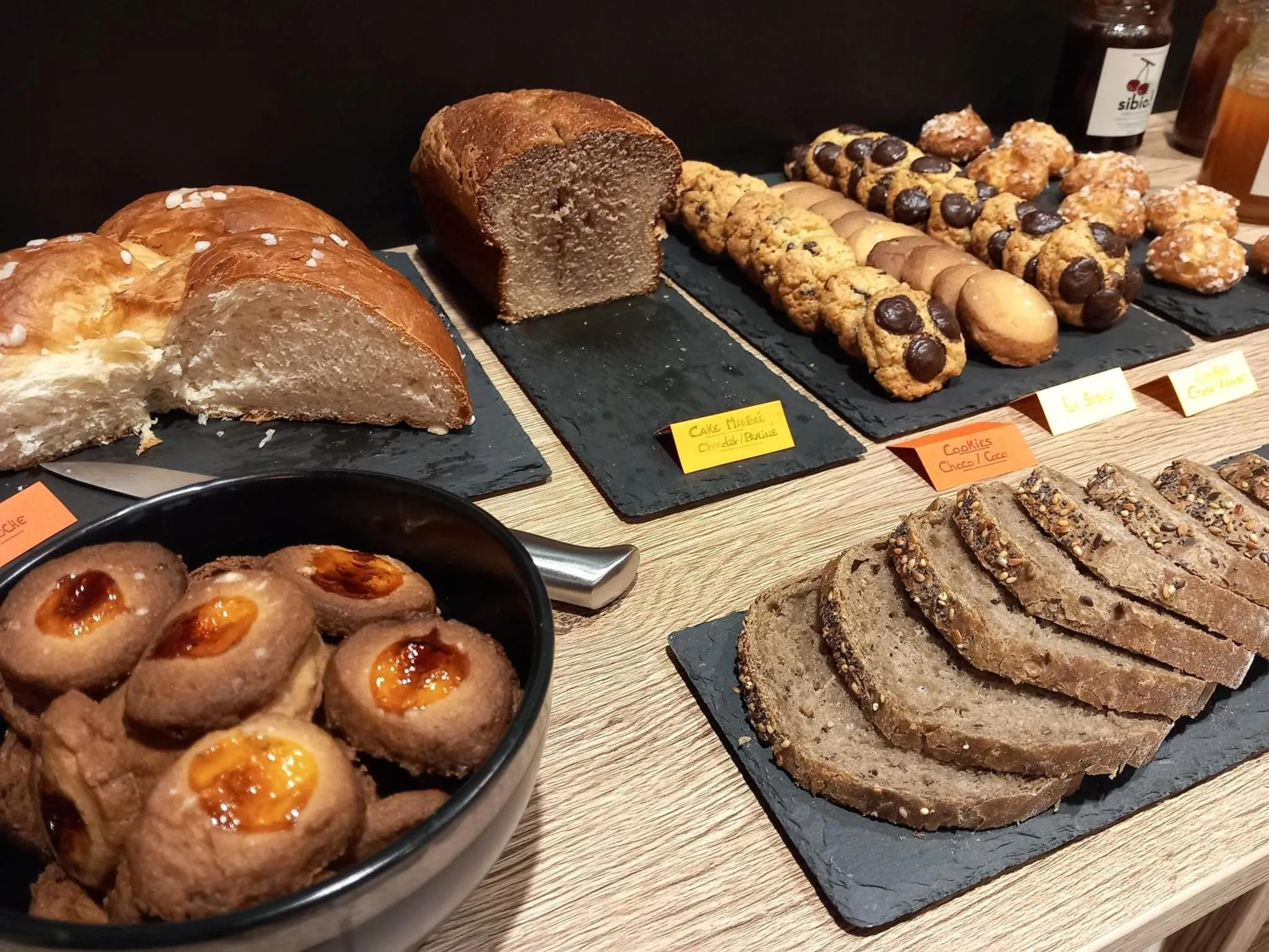 Présentation de viennoiseries et de pains sur un comptoir en bois.