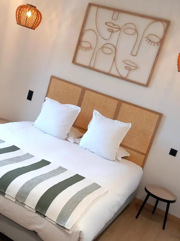 Une chambre lumineuse avec un lit recouvert de coussins blancs et d'une couverture verte.