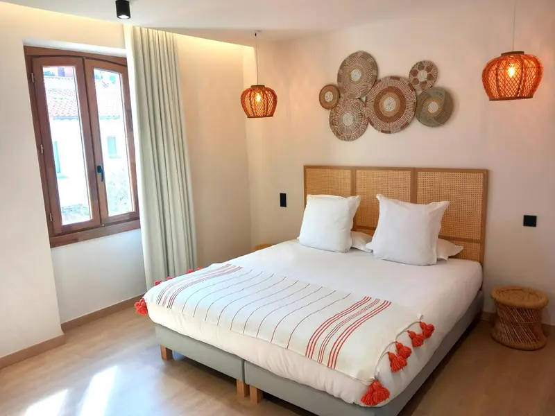 Une chambre lumineuse avec un grand lit et une décoration murale en rotin.