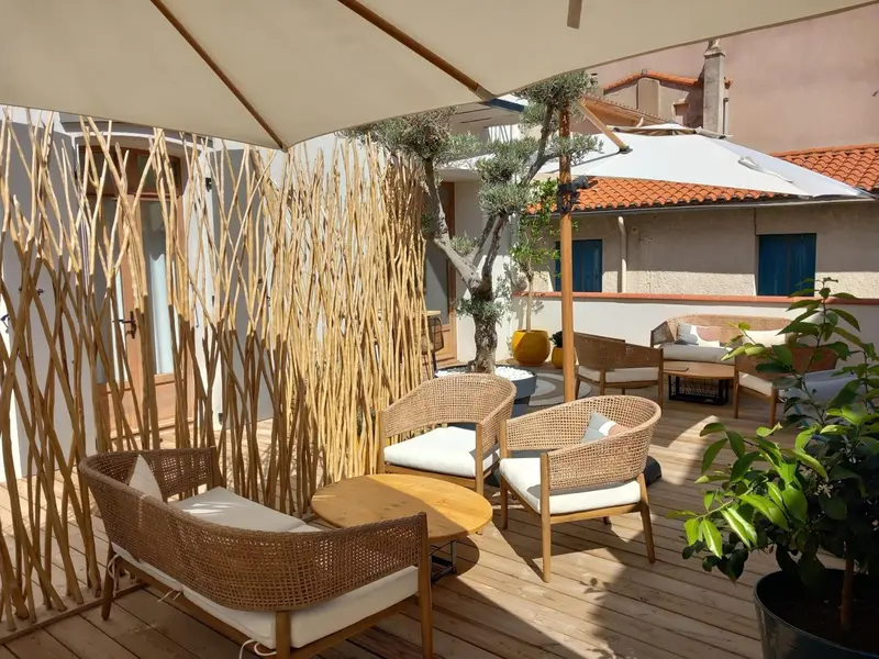 Espace de détente extérieur avec mobilier en rotin et parasols.