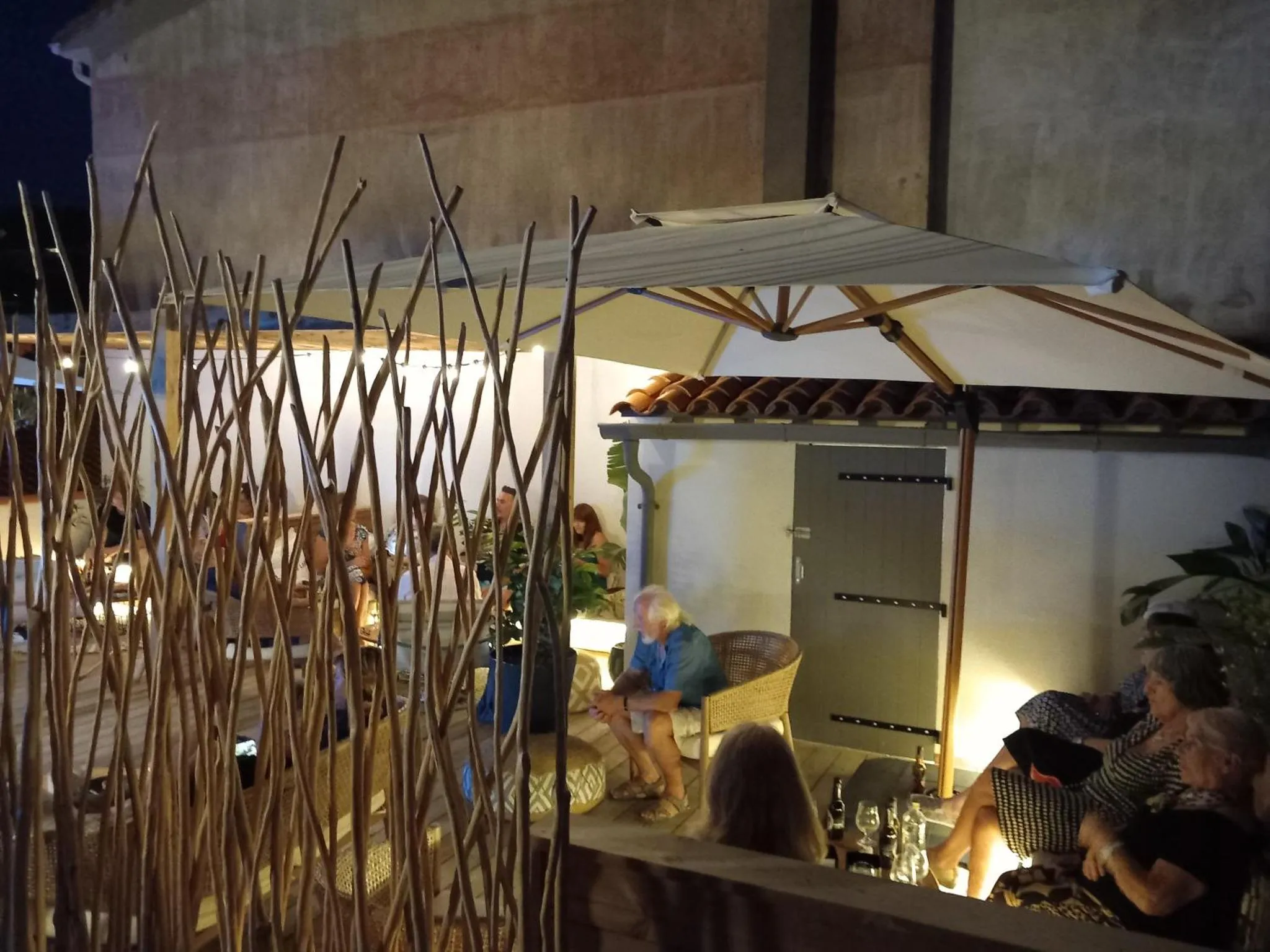 Une terrasse ombragée avec des tables et des chaises accueille des clients.