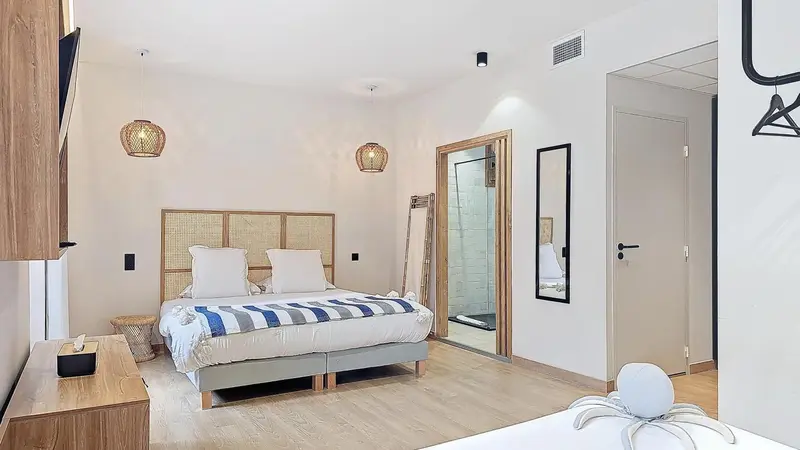 Une chambre lumineuse avec un grand lit recouvert d'une couette à rayures.