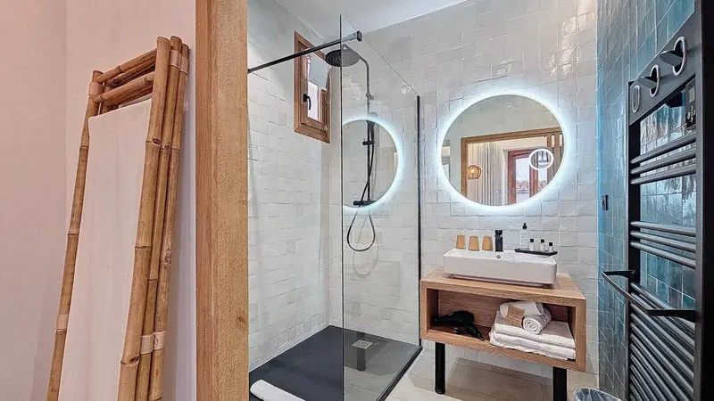 Une salle de bain moderne avec douche à l'italienne et miroir lumineux.