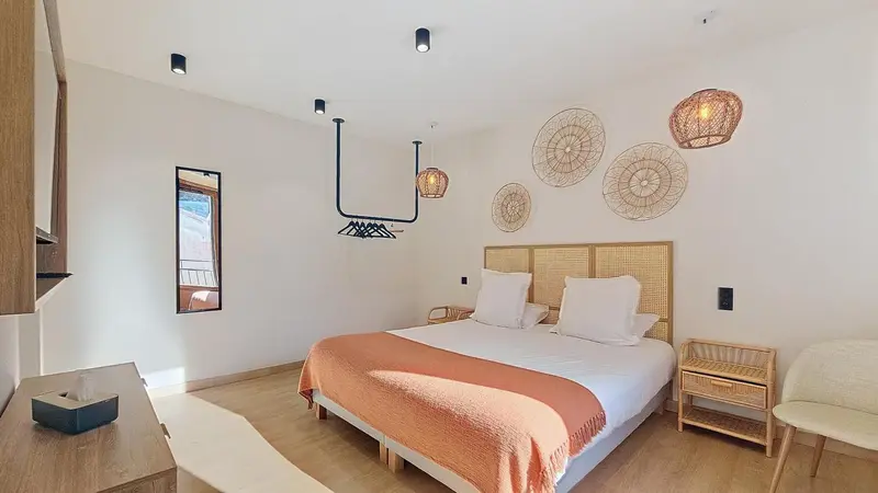 Une chambre lumineuse avec un grand lit recouvert d'une couverture colorée.