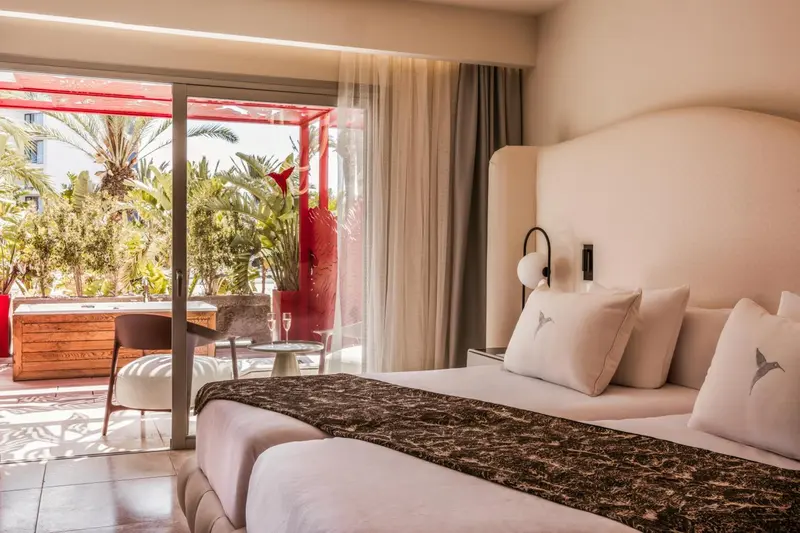 Une chambre lumineuse avec un grand lit et un accès à une terrasse.