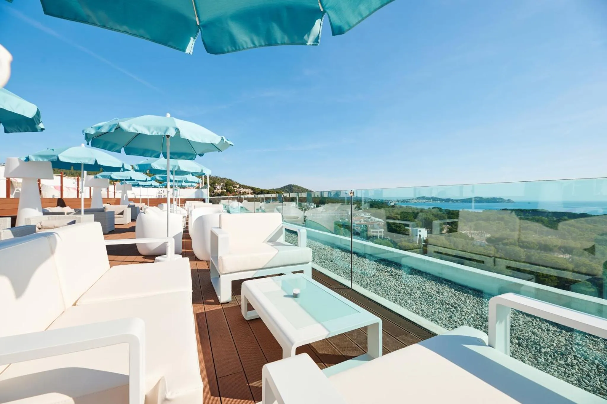 Terrasse aménagée avec des transats blancs et une vue sur la mer.